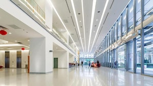 Ein großzügiges, modernes Interieur mit hoher Decke, Glasgeländern und einem zentralen Durchgang.