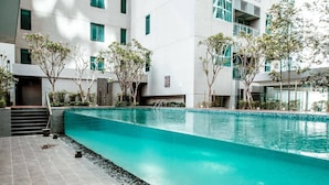 Ein moderner, überdachter Swimmingpool mit klarem, blauen Wasser, umgeben von einer gefliesten Terrasse und kleinen Bäumen.
