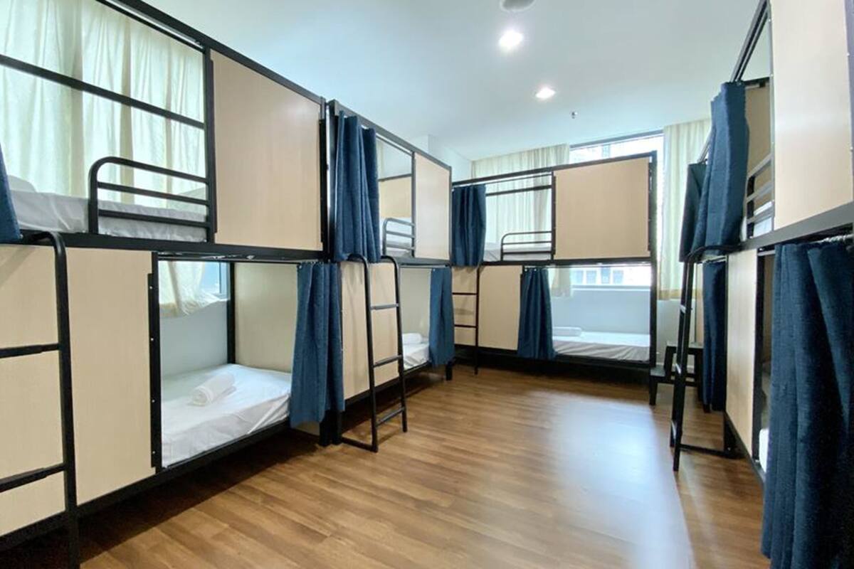 Un dormitorio con literas, suelo de madera y cortinas.