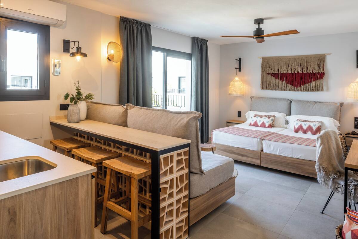Une chambre à coucher moderne, équipée d’un lit, de tables de chevet, d’un bureau et offrant une vue sur l’extérieur.