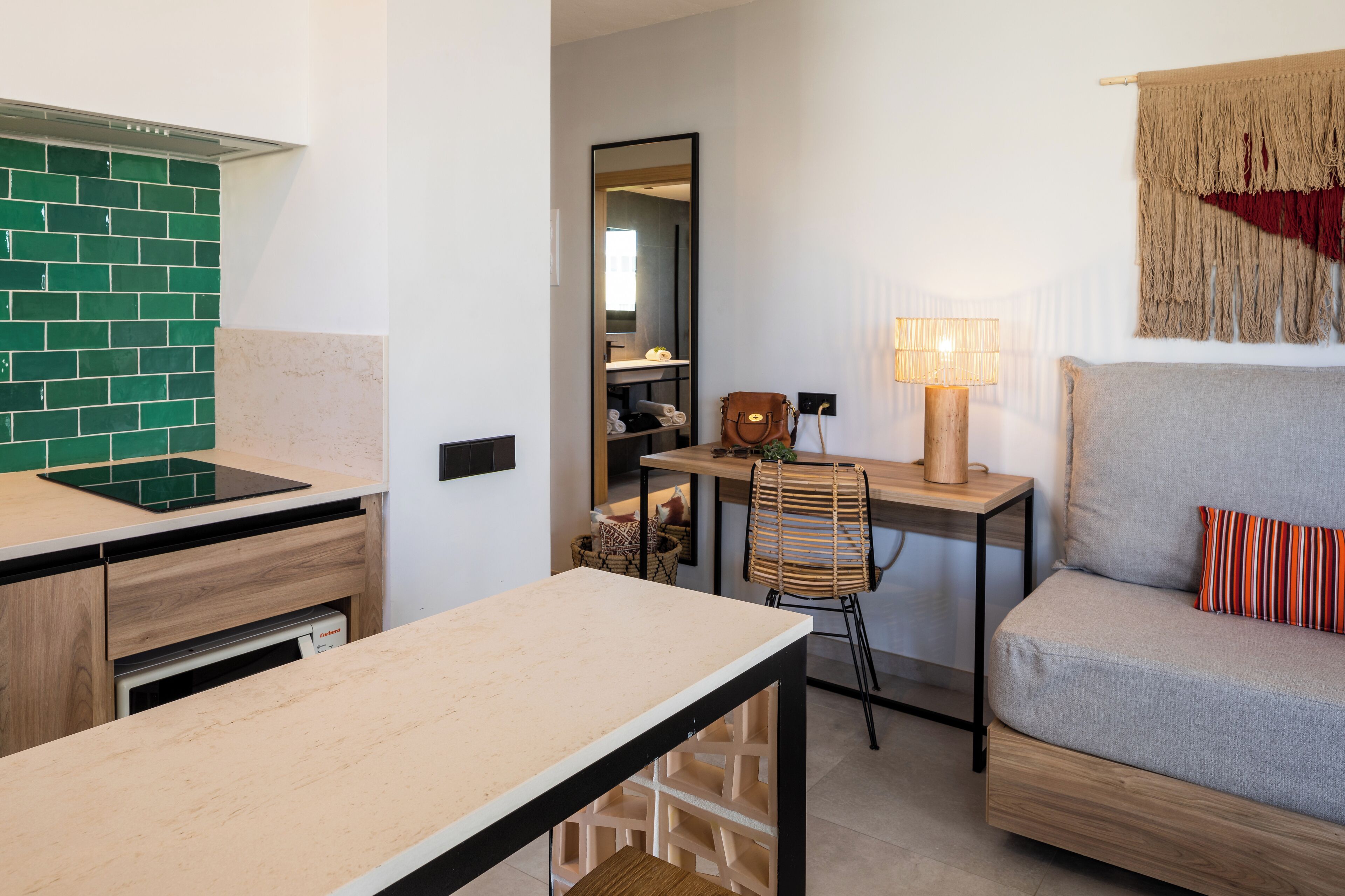 A compact living space with a kitchenette, a dining table, a sofa, and a chair.