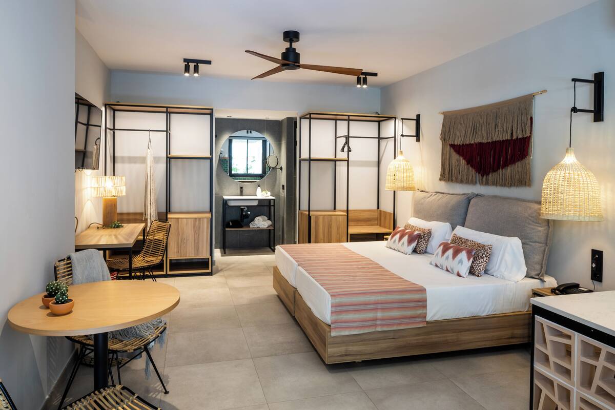 Une chambre moderne avec un lit, une table de chevet, une lampe et une petite table avec des chaises.