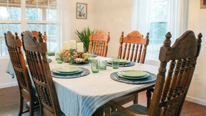 A dining room with a wooden table set for four, surrounded by matching chairs.