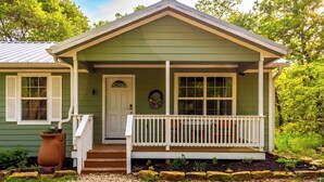 A green house with a porch, a front door, and a small garden area.