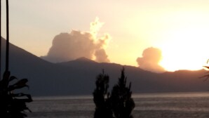 Un coucher de soleil sur une étendue d’eau, avec des montagnes en arrière-plan.