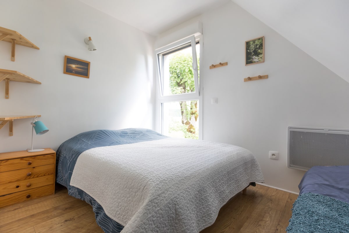 Une chambre à coucher avec un lit, une table de chevet, une fenêtre et un radiateur.