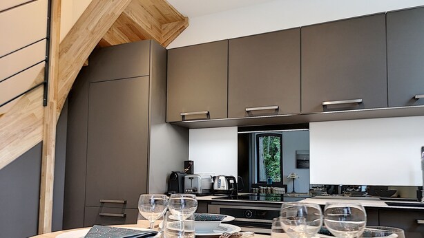Een moderne keuken met donkere kastjes, een houten plafond en een eethoek gedekt voor een maaltijd.