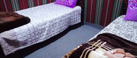 A room with two beds, striped wallpaper, and a patterned carpet.