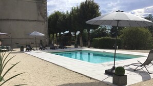 Una piscina rettangolare con bordo piastrellato, circondata da lettini e ombrelloni.