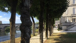 Un parco con alberi, un fiume e un ponte sullo sfondo.