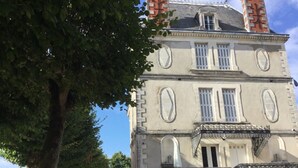 Un edificio storico con una facciata simmetrica, un ingresso centrale e una scala che conduce a un piano superiore.