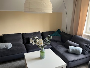 A modern living room with a sectional sofa, a white coffee table, and a vase of flowers.