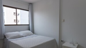 Ett litet, rent rum med en säng, ett fönster och ett litet bord med en apparat på.