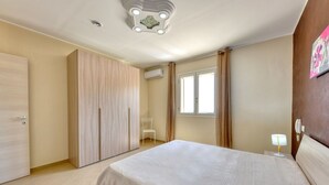 Une chambre à coucher comprenant un lit, une armoire, une fenêtre et un luminaire au plafond.