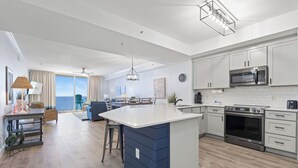A modern kitchen with a central island, stainless steel appliances, and a view to the outside.