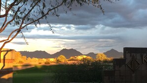 Un parcours de golf offrant une vue sur les montagnes et un ciel nuageux.