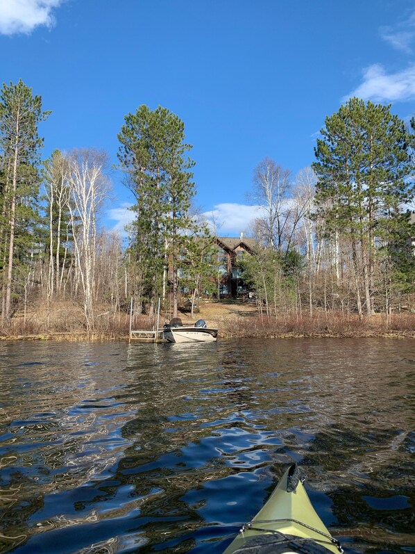 Un kayak su un fiume tranquillo, sullo sfondo alberi e una baita.