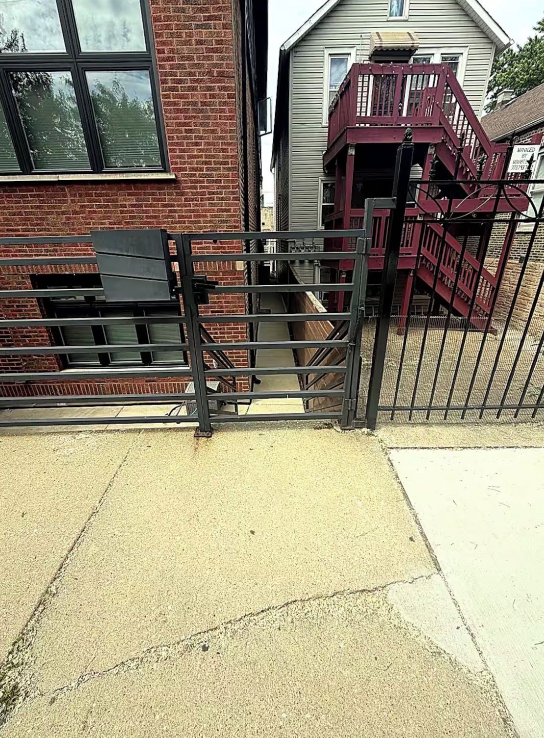 A gated area with a brick building and a red staircase.