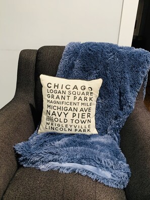 A chair with a dark fabric and a blue fuzzy throw blanket.