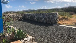A stone wall with a gravel path leading to a building with a blue roof.