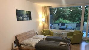 Un dormitorio con una cama de madera, una mesita de noche pequeña, una silla y vistas a un patio exterior.