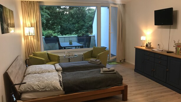 Un dormitorio con cama, una mesita y vista al exterior.