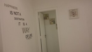 Une pièce dont le mur est orné d’une citation inspirante, une porte donnant sur une autre pièce et un tableau encadré accroché au mur.