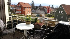 A balcony with a table and chairs, potted plants, and a view of houses. - Apartment am Kurpark - beautiful, quiet and right in the middle -  (St. Andreasberg)