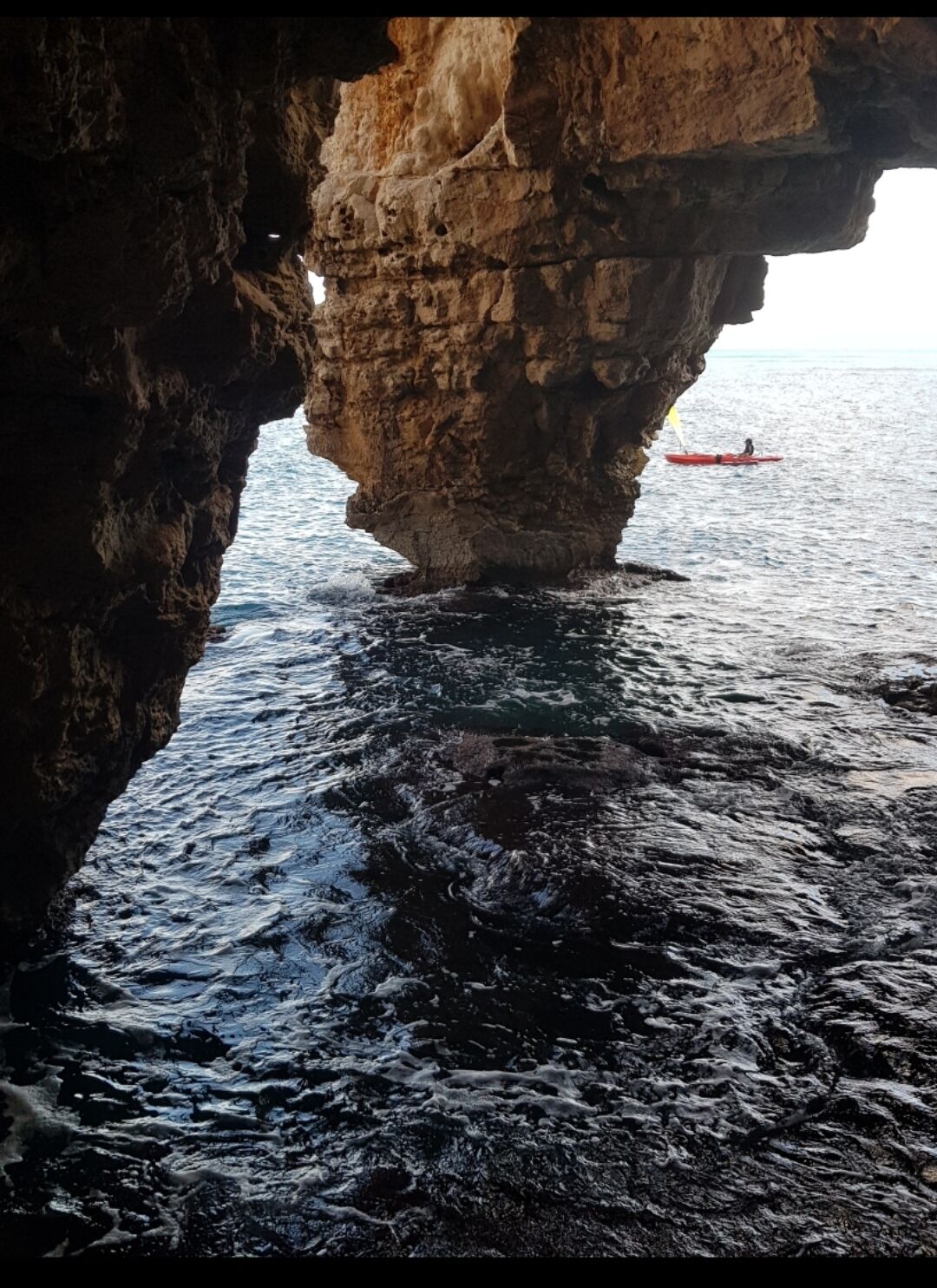 A natural rock formation with a cave opening to the sea.