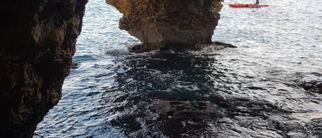 A natural rock formation with a cave opening to the sea.