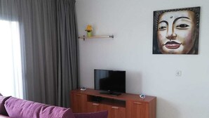 A modern living room with a purple sofa, a flat-screen TV on a wooden stand, and a painting on the wall. - RESIDENTIAL JANDIA MARINA 111 (Morro Jable)