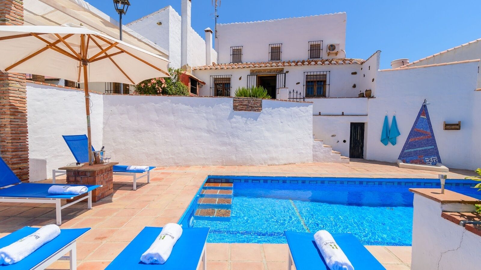 A swimming pool with blue lounge chairs and a brick wall.