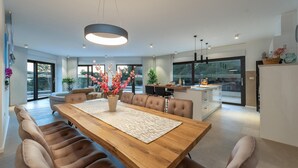 A modern kitchen with a dining area, featuring a wooden table, chairs, and a central light fixture. - Cozy home in Biograd na moru with sauna (Biograd na moru)