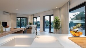 A modern kitchen with a large white sink, stainless steel faucet, and a wooden countertop. There are large windows providing natural light and views of the outdoors. - Cozy home in Biograd na moru with sauna (Biograd na moru)
