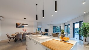A modern kitchen with a central island, pendant lighting, and a dining area with a view. - Cozy home in Biograd na moru with sauna (Biograd na moru)