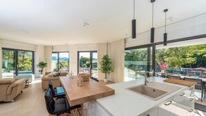 A modern kitchen with a large island, a dining area with a view, and a living space with a sofa and a coffee table. - Cozy home in Biograd na moru with sauna (Biograd na moru)