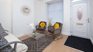 A modern living room with a sofa, two armchairs, a glass coffee table, and a decorative mirror. - Bachuss Lodge (Birmingham)
