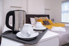 A hotel room with a bed, pillows, a tray with a kettle, cups, and a spoon. - Bachuss Lodge (Birmingham)