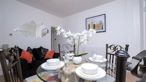 A dining area with a glass table, white plates, and a vase with white flowers. - Bachuss Lodge (Birmingham)