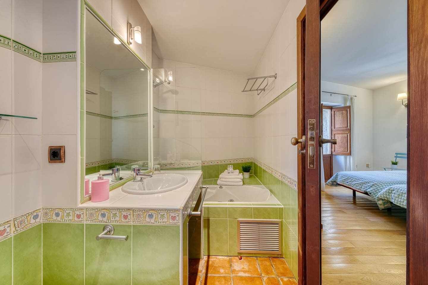 Une salle de bain équipée d’un lavabo, d’un miroir et d’une douche. On y trouve également un porte-serviettes et une porte qui donne sur une autre pièce.