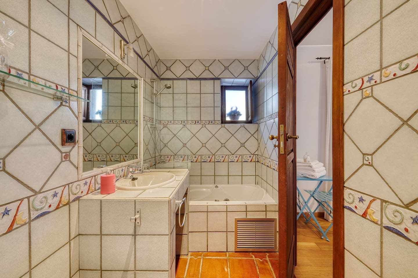 Une salle de bain avec un grand miroir, deux lavabos, une baignoire et une fenêtre.