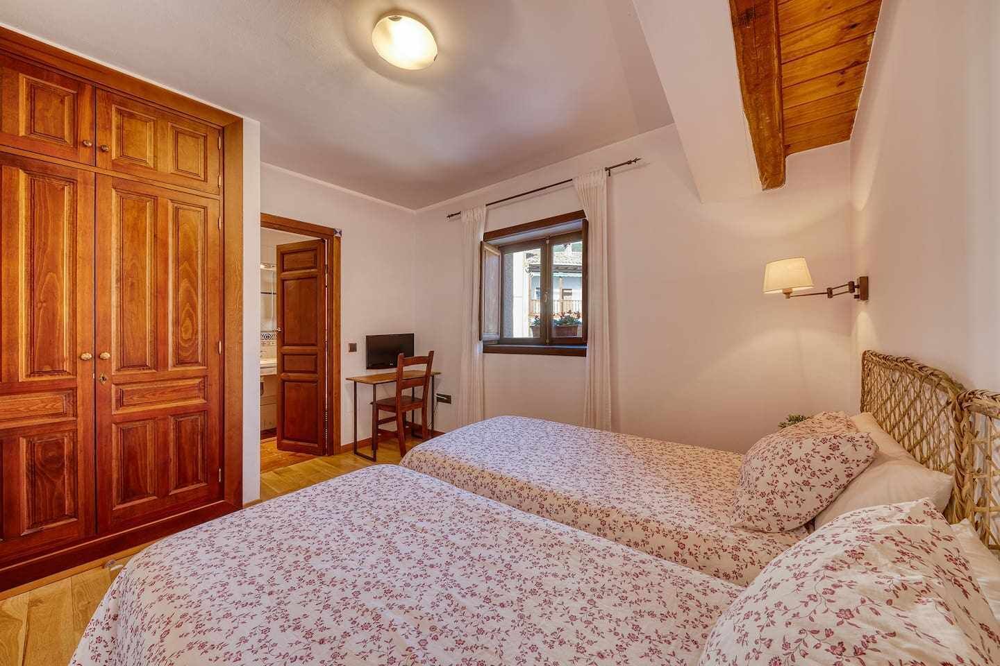 Un dormitorio con dos camas, un escritorio y una ventana.