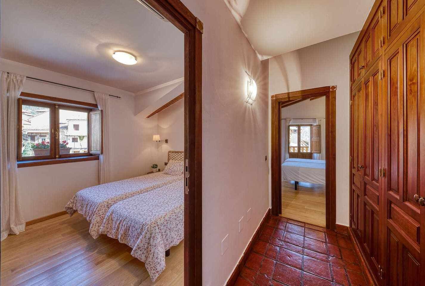 Un dormitorio con una cama, una mesita de noche, un ventanal y un armario de madera.