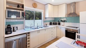 Een moderne keuken met witte kasten, een RVS vaatwasser, een magnetron, een broodrooster en een spoelbak.