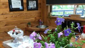 A wooden counter with a sink, framed artwork, and a potted plant with purple flowers.