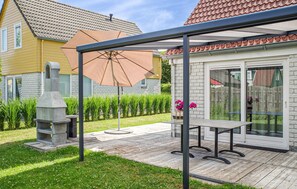 Een terras met een tafel, stoelen, een stenen open haard en een grote parasol.