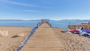 Un muelle de madera que conduce a un muro de piedra, con kayaks y un cartel.