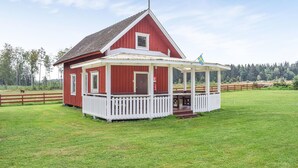 Een rode houten woning met veranda en vlag.