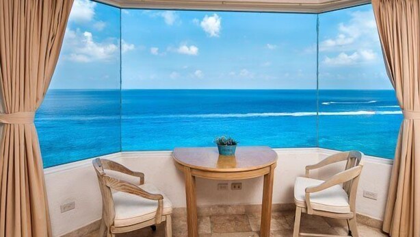 A room with a view of the ocean, featuring two chairs and a small table. - Amazing Ocean Views (Cozumel)