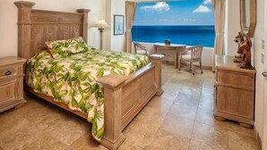 A bedroom with a bed, a desk, and a view of the ocean. - Amazing Ocean Views (Cozumel)